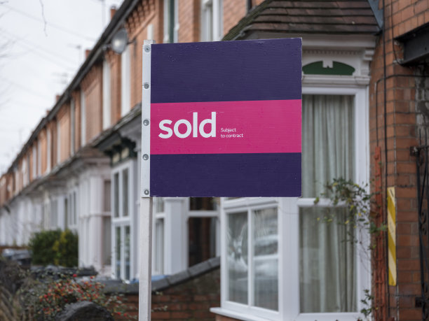 一排郊区的联排别墅，外面挂着“售出”的牌子。图片下载