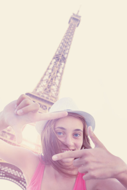 一个快乐的女人在埃菲尔铁塔上用手指做相框图片下载