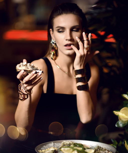 美丽性感时尚的黑发女人在昂贵的室内餐厅吃牡蛎等图片下载