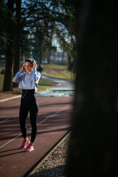 年轻女运动员戴着耳机跑步图片下载