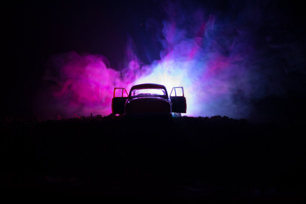 剪影的老旧汽车在黑暗的雾色调背景与发光灯在低光，或剪影的旧犯罪车黑暗的背景。图片下载