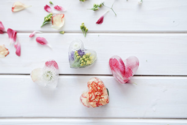 花瓣和心形的冰块，里面有花，在白色的木质背景上图片下载
