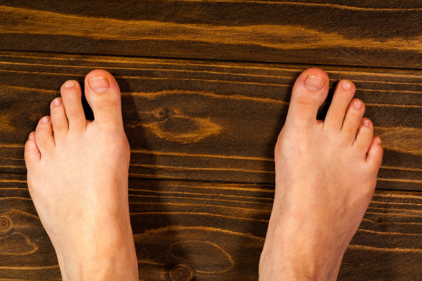 近一个女人痒脚用他的大脚趾抓他的另一只脚在木地板上图片下载