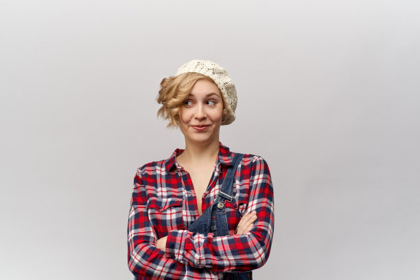 特写肖像在高分辨率年轻的微笑女孩卷，长头发的女孩。格子衬衫，连衣裤和帽子的复古风格。图片下载