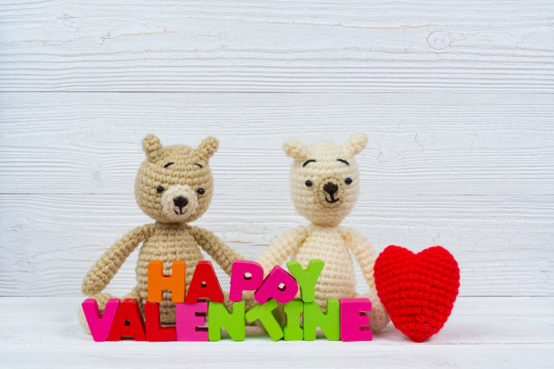 甜蜜的夫妇泰迪熊娃娃在爱与情人节文字和红色编织心在白色木制背景和复制空间添加文字和图片，爱和情人节的概念。图片下载