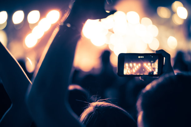 抽象的彩色背景手持智能手机，通过捕捉图像照片和录制视频的灯光和人群拥挤的音乐会音乐活动的记忆。使用相机移动概念。图片下载