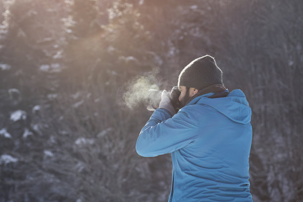 摄影师在冬天的森林里拍照图片下载