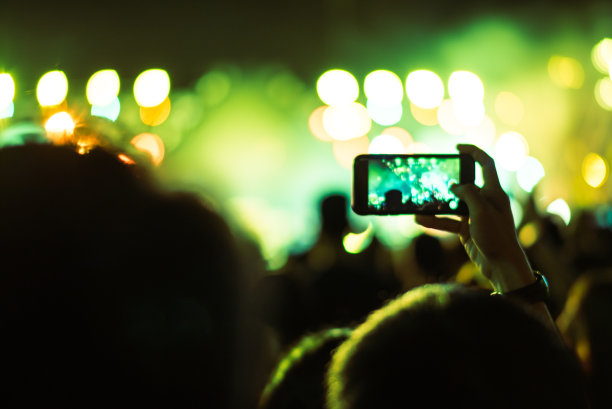 抽象的彩色背景手持智能手机，通过捕捉图像照片和录制视频的灯光和人群拥挤的音乐会音乐活动的记忆。使用相机移动概念。图片下载