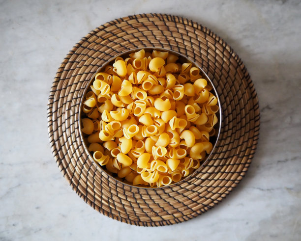 生意大利面食叫“管状”，在英语中是条纹管的意思。意大利面放在一个用稻草做成的圆托盘里的碗里图片下载