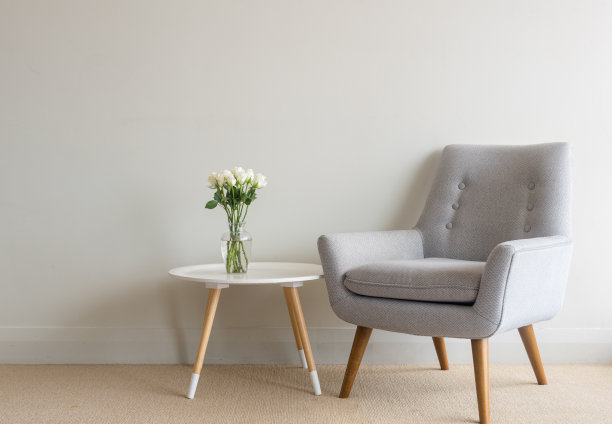 靠墙的桌子上放着复古扶手椅，花瓶里插着玫瑰花素材图片