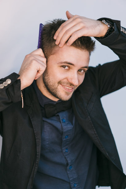 一个穿着正装的时髦英俊男子的肖像，抚摸着他的头发。图片下载