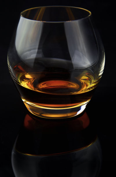 倾斜的威士忌在黑色的背景图片下载
