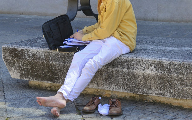 光着脚坐在长凳上工作的人图片下载