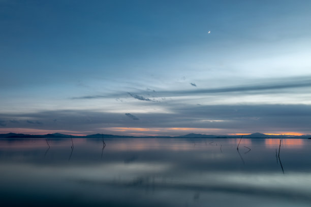 黄昏时分，美丽的trasiimeno湖(翁布里亚，意大利)，蓝色和橙色的色调和天空中的月亮图片下载