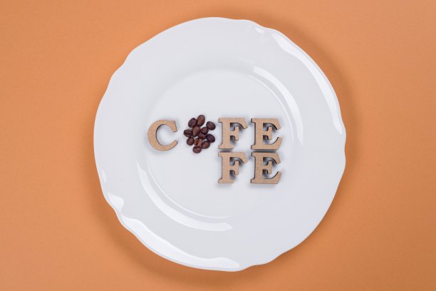 “咖啡”这个词是用抽象的木头字母写成的。橙色背景白色板。图片下载