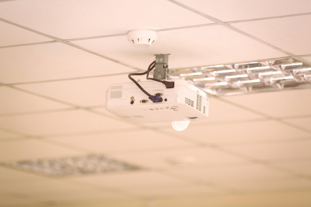 多媒体投影仪悬挂在现代会议室的天花板上，室内黑白画面图片下载