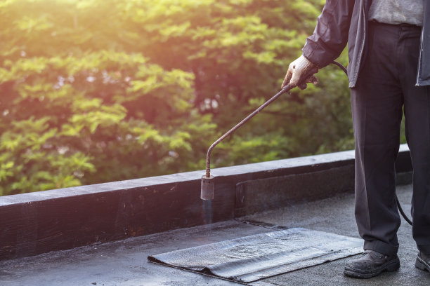 一群工人在建筑物屋顶安装焦油箔。气、火点火防水系统图片下载
