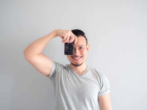 一名男子拿着一架无反光镜照相机试图拍照。图片下载