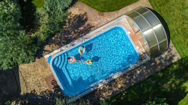 从上面鸟瞰游泳池里的一家人，快乐的妈妈和孩子们在充气甜甜圈上游泳，在水上玩得很开心图片下载