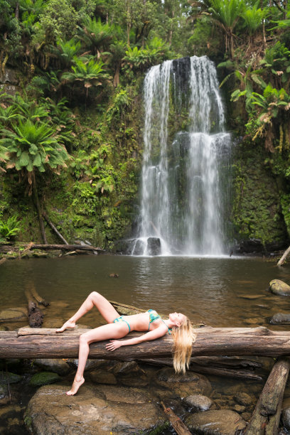 美丽的女人躺在原木前一个惊人的瀑布，回到自然，波尚瀑布，大洋路图片下载