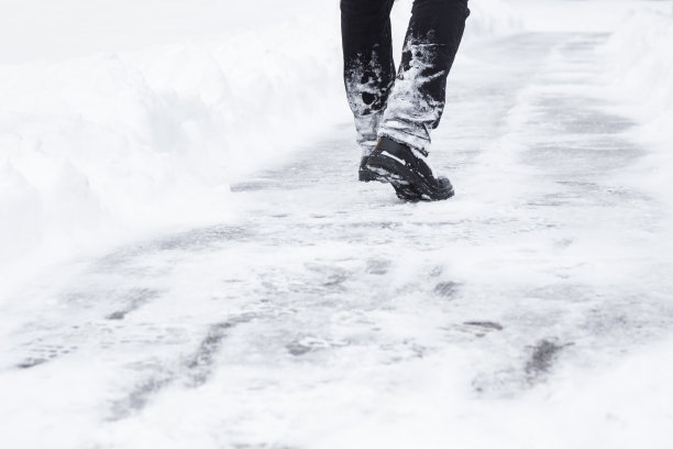 雪后在人行道上独自行走的黑衣男子图片下载