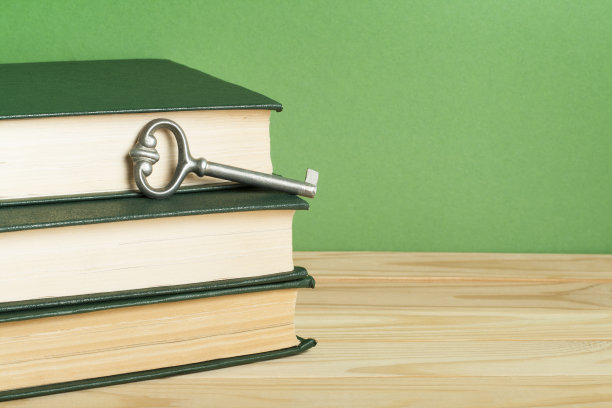 知识的关键。书与钥匙木制背景。图片下载