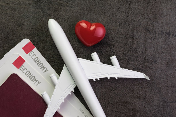 旅行爱好者，蜜月旅行或情人节礼物概念，玩具飞机，登机牌和护照，红粉色心形的黑色纹理黑板上有拷贝空间图片下载