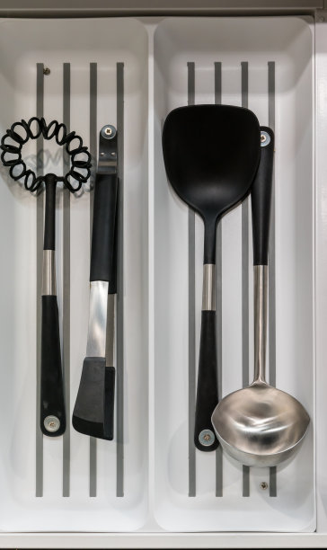 厨房的抽屉里装满了塑料和不锈钢的炊具。功能的厨房空间。图片下载