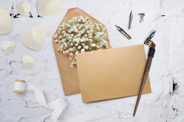 书法羽毛一个信封与鲜花和一封信，情人节贺卡与地方为您的文字。平躺，俯视图照片模拟图片下载