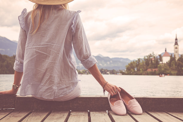 孤独的女孩坐在湖边的木码头上。图片下载