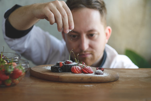 一个集中的男性糕点厨师在厨房装饰甜点的特写图片下载