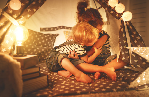 快乐的家庭小朋友们在黑暗的帐篷里玩耍、欢笑和拥抱图片下载