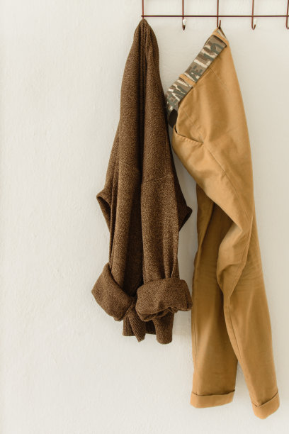 长款针织毛衣和一条暖色的裤子挂在墙上的拐杖上，文字空间图片下载