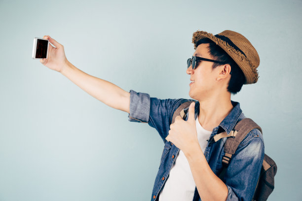 年轻的亚洲游客微笑着在淡蓝色背景下自拍图片下载