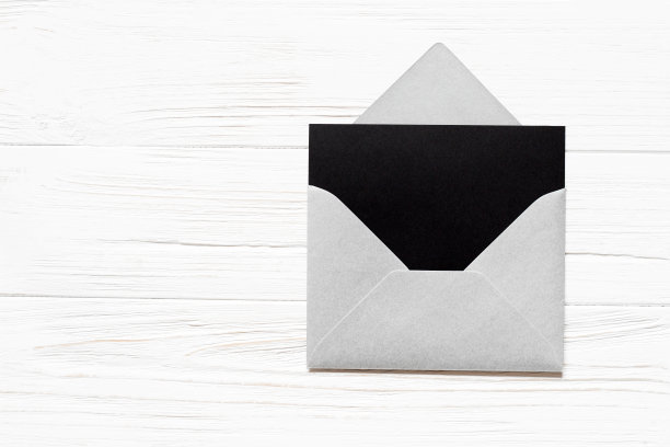 打开银色信封，白色木质背景上空白的黑色纸。贺卡模型。图片下载