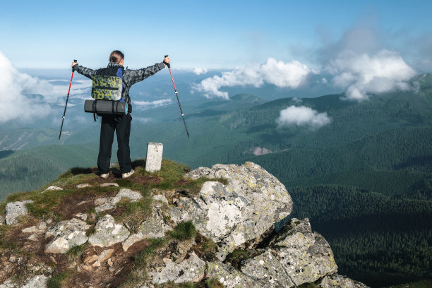 徒步旅行者站在山顶上，欣赏着山脉的景色图片下载
