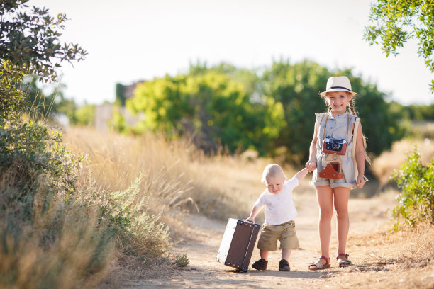 一个弟弟带着一个姐姐和一个大行李箱一起旅行图片下载