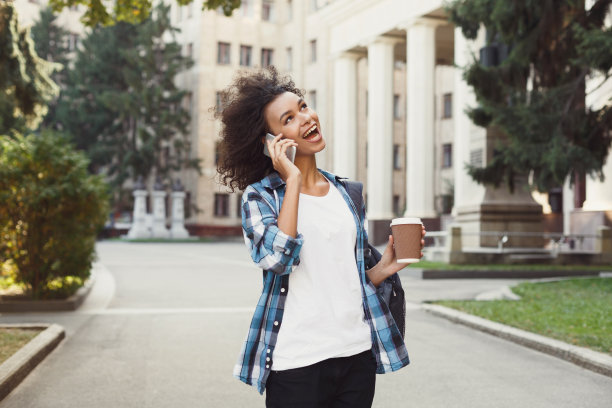 学生女孩背包和移动在大学建筑背景图片下载