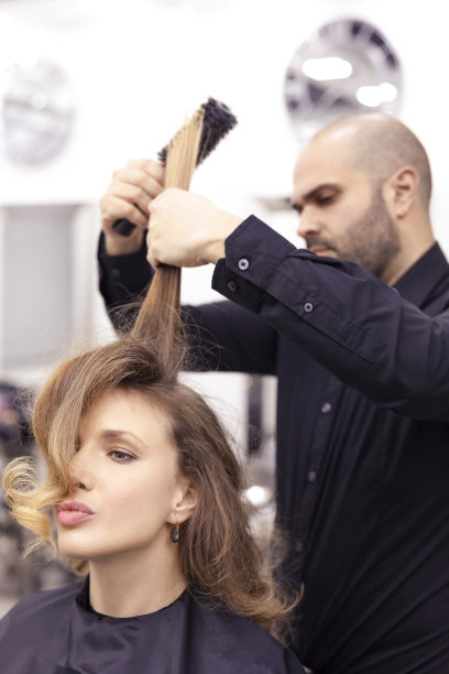 理发师在行动中吹，吹干长发，卷头发。一个美发沙龙里的美女图片下载