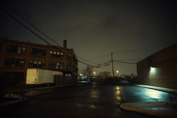 黑暗和空的城市停车场与一个老式的工业仓库工厂大楼和一辆卡车半挂车在晚上图片下载