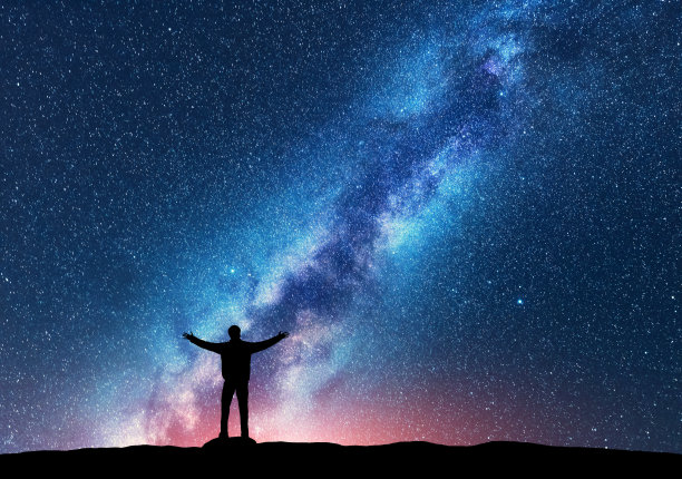 空间。银河的剪影，一个快乐的人举起手臂站在山上。夜景与美丽的银河。宇宙。夜空繁星满天，银河五彩缤纷。星空与人图片下载
