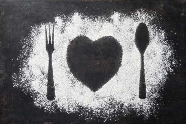 勺子，叉子和盘子做成心形，面粉撒在深色的盘子周围图片下载