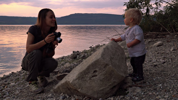 母亲在日落时给她的孩子拍照图片下载