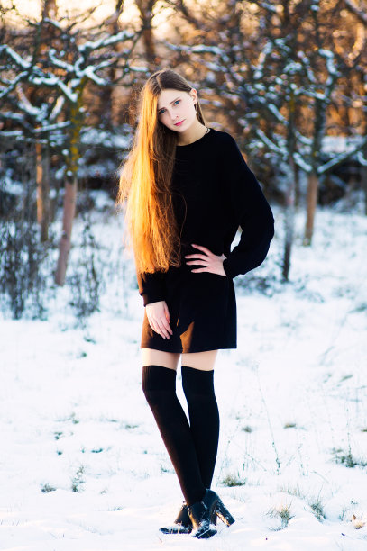 一个时尚模特在冬天的院子里穿着黑色的裙子拍照片图片下载