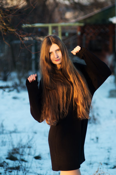 一个时尚模特在冬天的院子里穿着黑色的裙子拍照片图片下载
