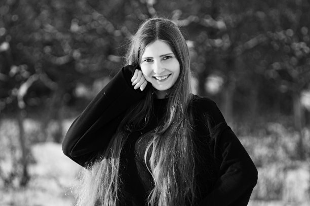 一个时尚模特在冬天的院子里穿着黑色的裙子拍照片图片下载