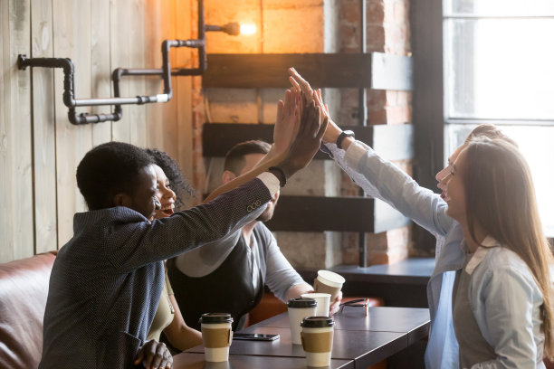 各种各样的朋友在咖啡馆聚会时一起举手击掌图片下载