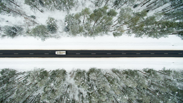 冬季森林和柏油路。从以上观点。这张照片是用无人机拍摄的。松树和冷杉林在雪地里图片下载