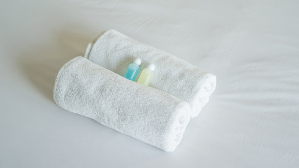 白色毛巾、洗发精和肥皂放在床上。图片下载