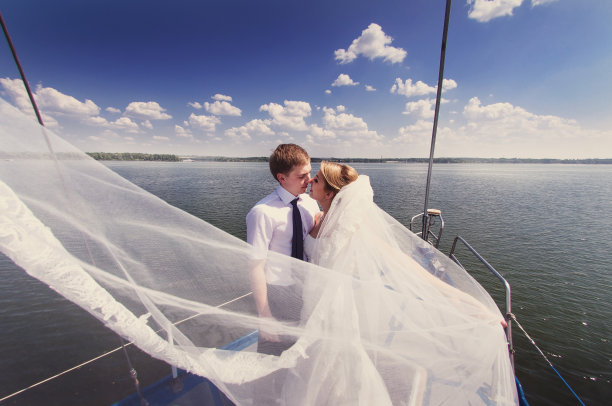 蜜月航行。新娘和新郎坐在帆船的船头图片下载